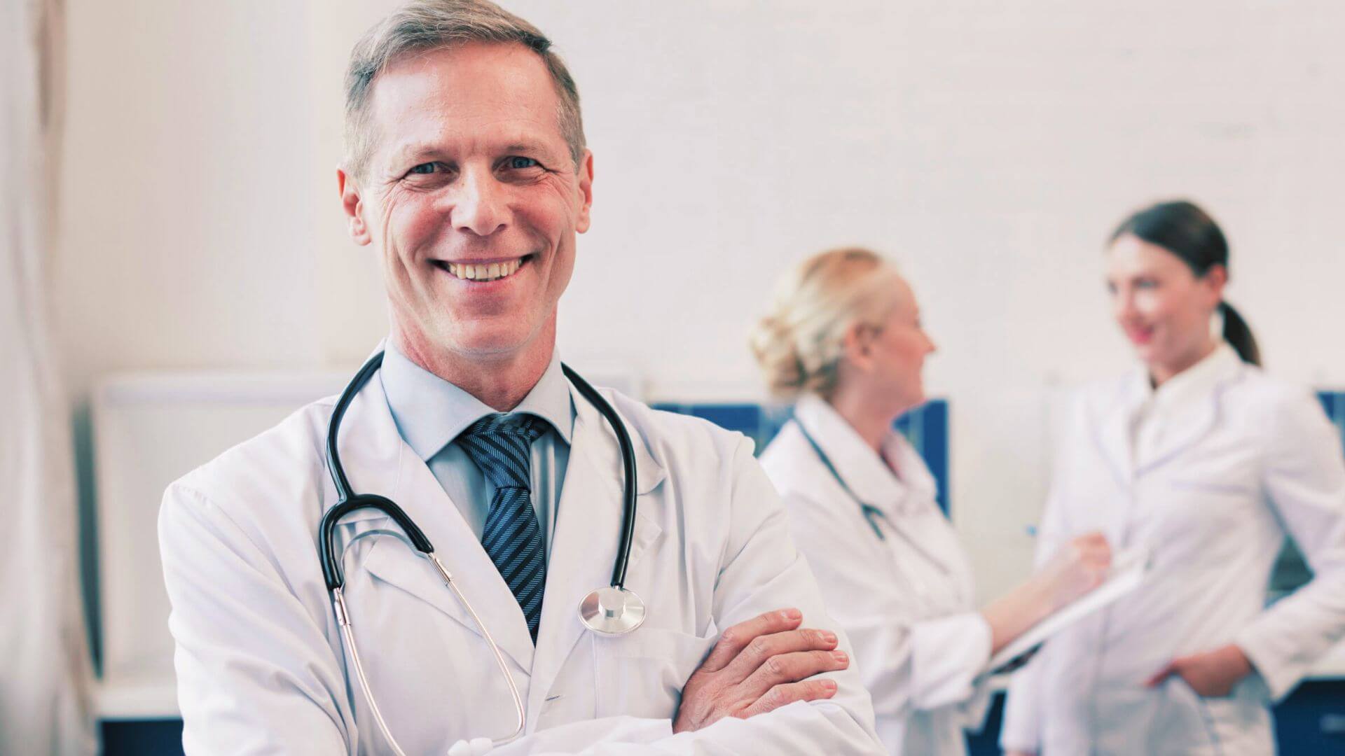 Doctor in a white coat looking directly at camera, warm confident expression